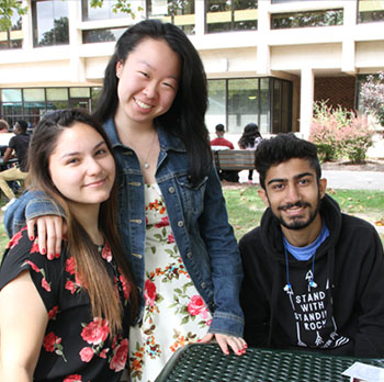 Three students socializing on the campus quad